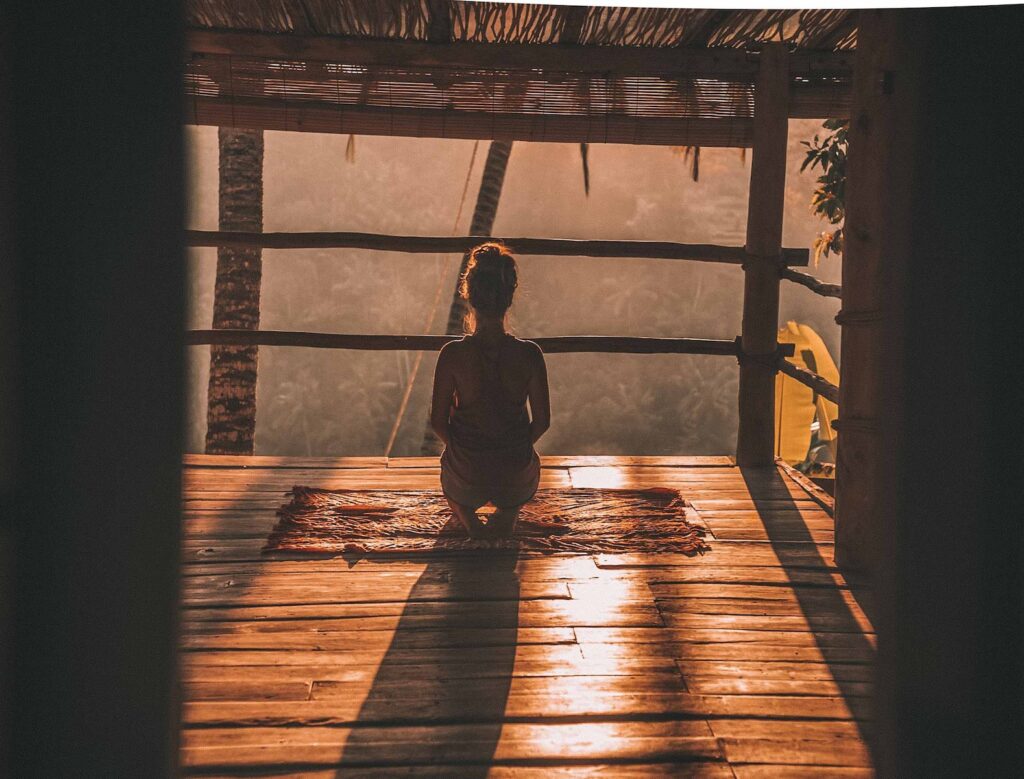 meditação guiada, woman meditating on floor with overlooking view of trees