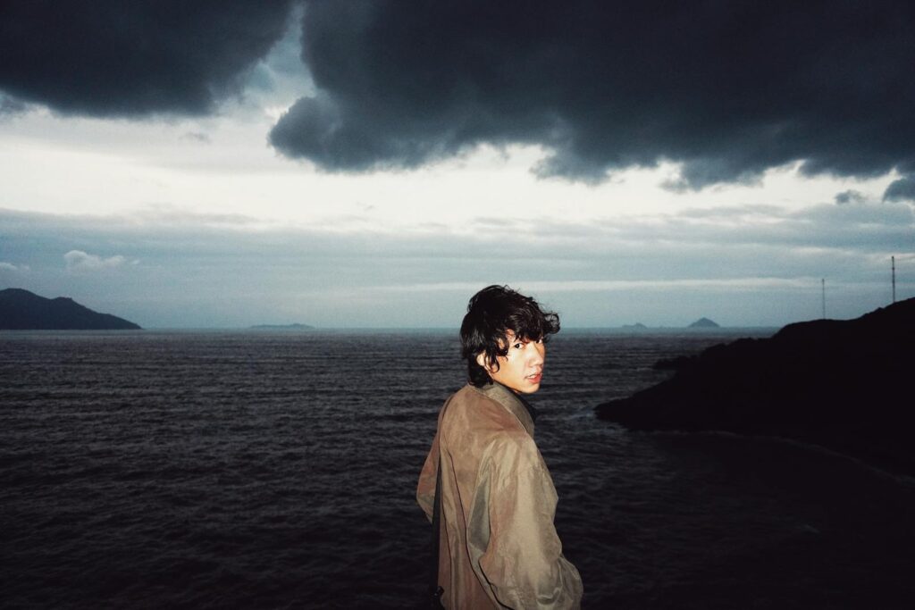 A woman standing on a cliff looking out at the ocean