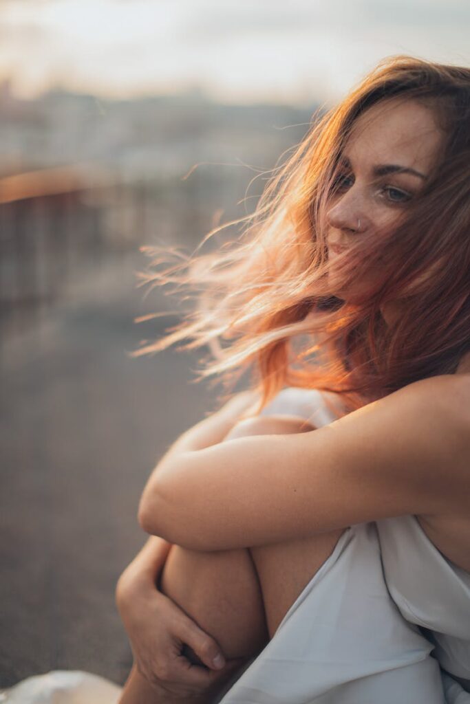 Young woman sitting on rooftop in windy weather