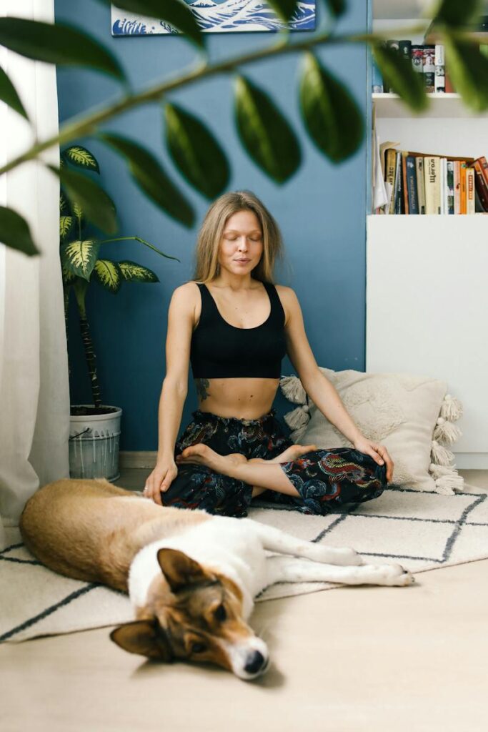 Woman in Black Tank Top and Black Floral Shorts Sitting on Bed Beside Brown and White