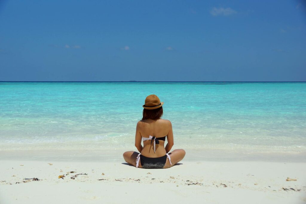 Woman Wearing Black and White Brassiere Sitting on White Sand