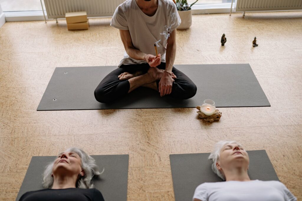 Man in White Crew Neck T-shirt and Black Pants Sitting on Yoga Mat