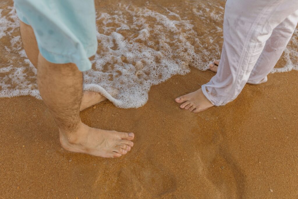 a man and a woman standing on a beach next to the ocean