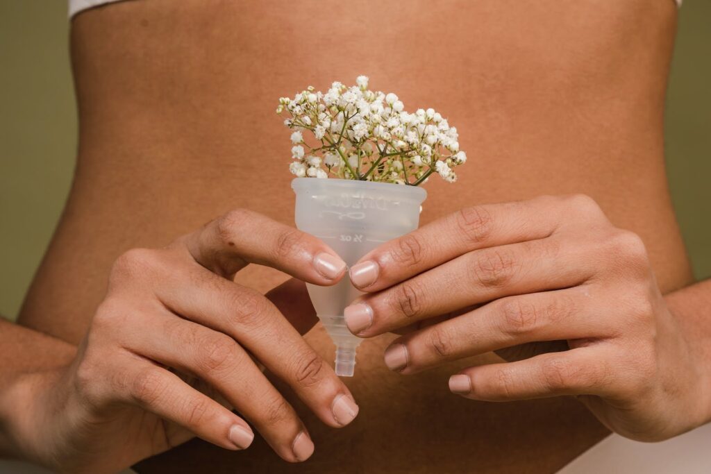 Crop woman with tiny plant in menstrual cup