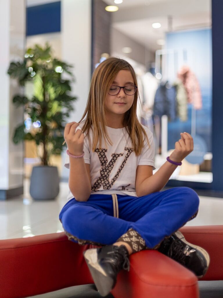 Young Model in Louis Vuitton Clothes Meditating Sitting Cross-legged in a Shopping Mall