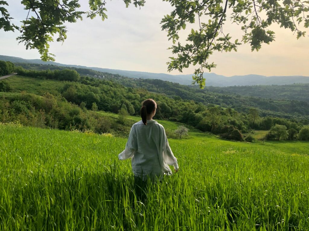 A woman sitting in a field with a view of the mountains