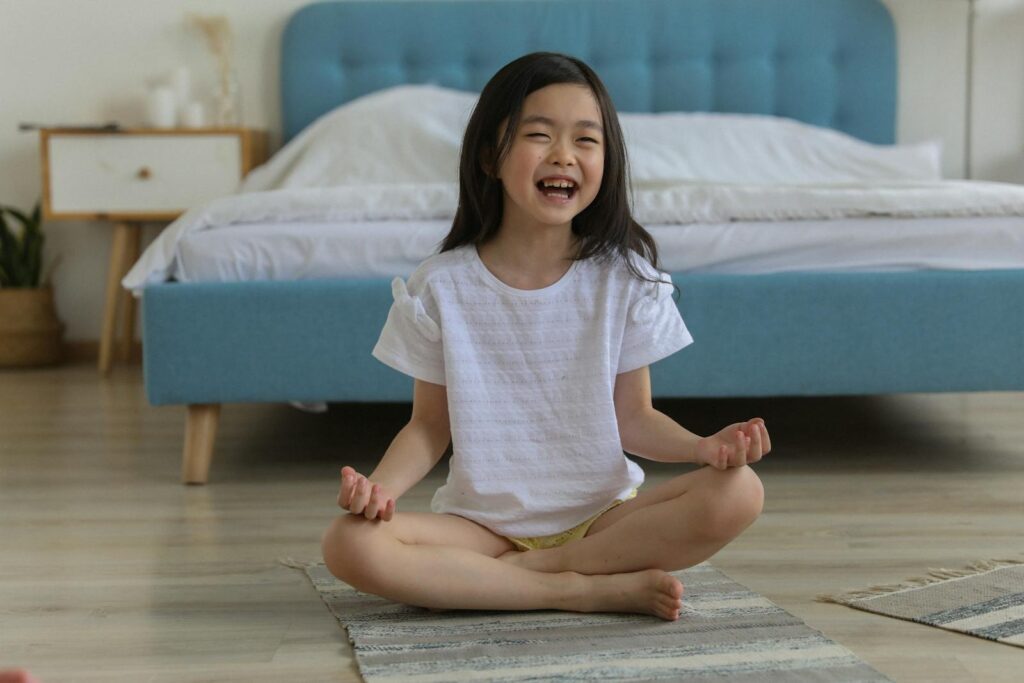 Happy Asian girl laughing while resting in room with legs crossed